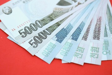 North Korean won money bills in big amount lies on red color table close up