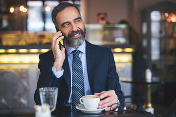 Senior businessman working and having a coffee in coffee bar
