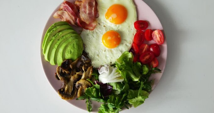 Round dish with bacon and small bright tomatoes stands on smooth modern table. Mushrooms and eggs strengthen immunity enriching body with nutrients at beakfast
