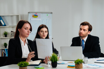 Three Professionals Discussing Business Reports at a Meeting