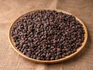 Raw Dark Brown Chickpeas (Kala Chana) on a rustic wooden table. Dry Balck chickpea (ceci neri) background close up.