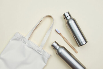 Flat lay eco friendly tote bag silver water bottles bamboo toothbrush suggesting sustainability [with copy space]