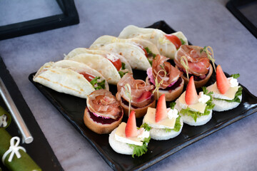 Buffet food for party decorated with fresh plants. Sandwiches with cheese and ham on table.  Catering buffet food indoor in luxury restaurant with meat and vegetables. Buffet table with delicacies