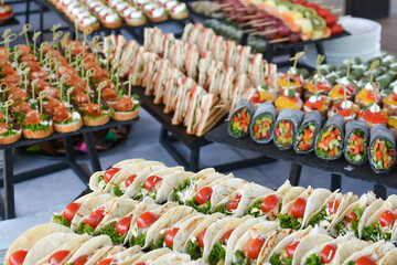 Buffet food for party decorated with fresh plants. Sandwiches with cheese and ham on table.  Catering buffet food indoor in luxury restaurant with meat and vegetables. Buffet table with delicacies