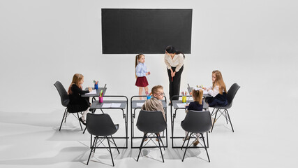 Student presenting in front of classroom while teacher listens kindly, classmates take notes. Student engagement, school learning, confidence building, primary education, classroom story time concept.