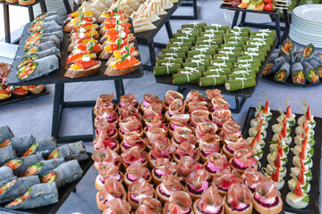 Buffet food for party decorated with fresh plants. Sandwiches with cheese and ham on table.  Catering buffet food indoor in luxury restaurant with meat and vegetables. Buffet table with delicacies