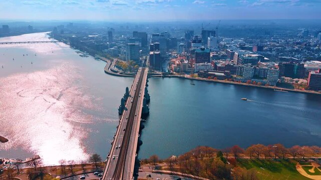 Surface of calm Charles River sparkles beautifully in the sun. Drone flight over the Longfellow Bridge with some cars on. Boston, Massachusetts, USA.