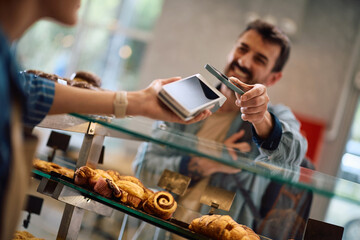 Close up of bakery customer paying with smart phone app.