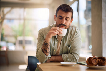 Mid adult man enjoying in cup of coffee at coffee shop.