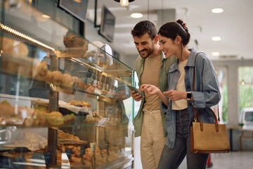 Happy couple buying pastry at bakery shop.
