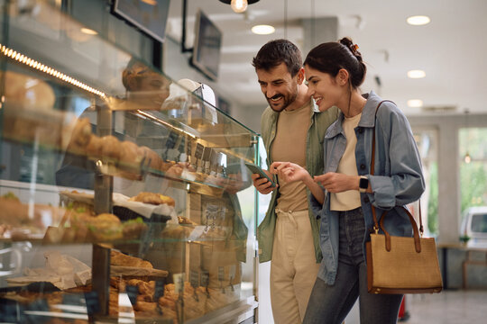 Happy couple buying pastry at bakery shop.
