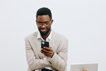 Modern young man with glasses using smartphone in an office setting, dressed in casual blazer, focused on screen, clean white background, technology lifestyle concept, professional appearance