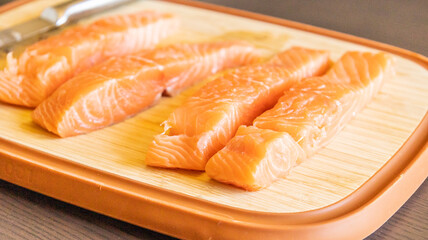 Close-up of fresh raw salmon fillets placed on a wooden cutting board