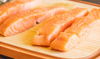 Close-up of fresh raw salmon fillets placed on a wooden cutting board