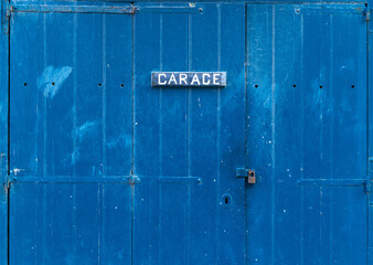 Blue wooden garage door with the inscription - Garage. Closed garage gate with a small lock on it