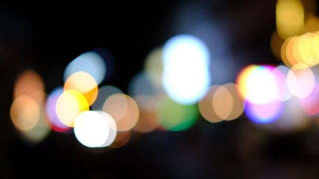 A blurry image of a city at night with lights and a yellow sign. The image has a dreamy, ethereal quality to it, as if it were a painting rather than a photograph