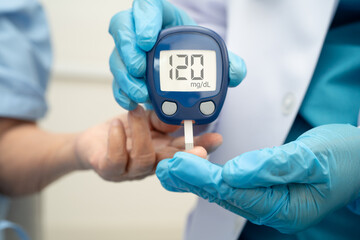 Asian doctor using digital glucose meter for check sample blood sugar level to treatment diabetes.
