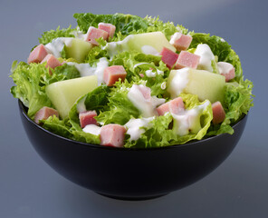 Salat mit Schinken und Melone, Schinkenwürfel, Obst, isoliert, schwarze Schale, 
