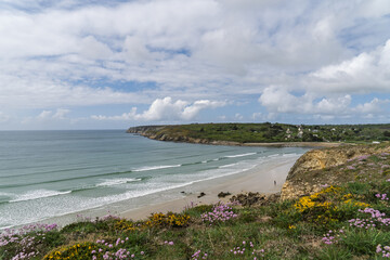 Lumière du printemps sur les falaises bretonnes, ajoncs fleuris et améries maritimes sous un ciel changeant.