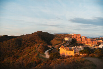 Picturesque hillside village with sunset-lit buildings and winding paths in Calahonda, Costa del...