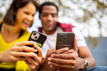 Close-up of two young friends holding smartphones side by side.