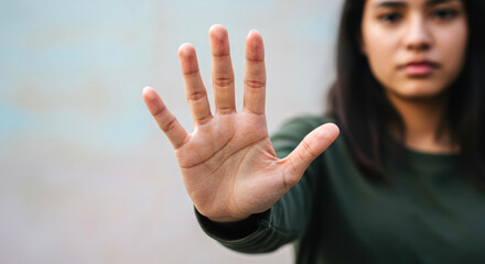 Young latina woman gesturing stop serious expression hand forward outdoors boundary setting. Stop gesture, boundary setting, serious refusal concept.