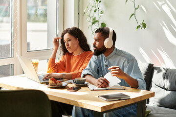 Couple collaborates on remote freelance projects in stylish cafe setting