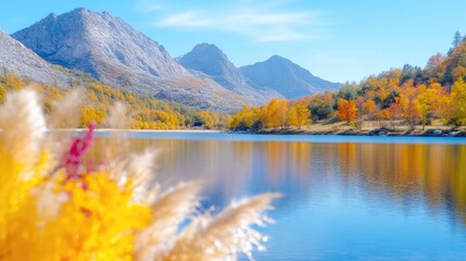 Naklejka premium Scenic alpine lake reflecting majestic mountains surrounded by colorful autumn foliage under a clear blue sky.