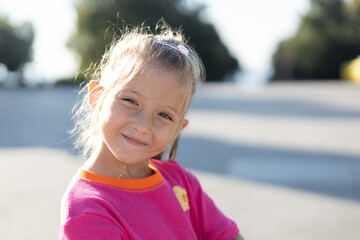 Happy little girl. Outdoor close-up portrait with soft natural light and a blurred background.
