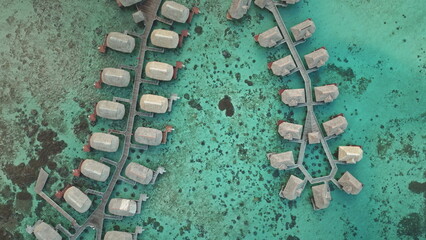 Aerial view breathtaking beauty of overwater bungalows in crystal clear turquoise water, tropical island, luxury idyllic vacation destination. Remote nature paradise, exotic summer travel background