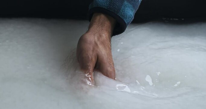 Super Slow Motion of Hand Stirring White Paper Pulp in Vat During Traditional Papermaking Process - Close-Up of Artisan Mixing Slurry for Sheet Formation in Handmade Paper Craft Workshop at 1000 fps.
