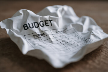 Crumpled budget paper on table symbolizes financial stress and debt that could lead to eviction notice for unpaid expenses and income imbalance