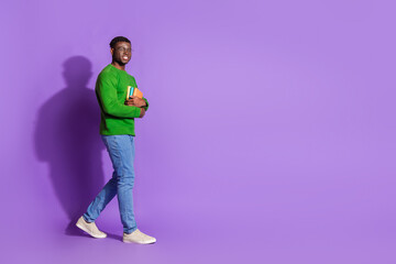 Confident Young Man in Stylish Green Outfit Holding Book on a Violet Background