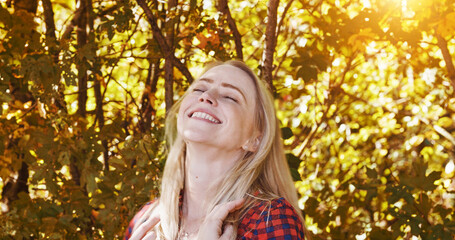 Sunshine, happy and woman by trees in morning for wellness, fresh air and relax outdoors. Countryside, smile and person in forest, woods and nature for calm, peace and freedom in natural environment