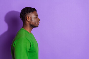 Side profile view of a stylish young man in a bright green sweatshirt against a vibrant purple...