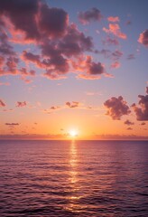 Obraz premium a vibrant sunset over the ocean casts a golden reflection on the rippling water beneath a sky filled with soft pink and orange clouds.