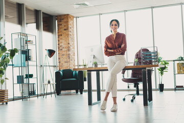 Confident businesswoman standing in modern office setting with professional attire and a stylish...