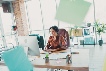 Professional woman in a modern office workstation illuminated by natural light, enthusiastically...
