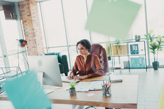 Professional woman in a modern office workstation illuminated by natural light, enthusiastically engaged in administrative work