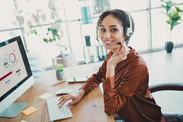 Young professional female wearing headset working in office environment, showcasing workplace...