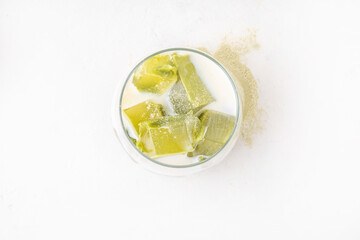 Matcha jelly latte, iced milky drink with green matcha tea jellatin cubes, trendy refreshing Iced non-caffeine healthy drink