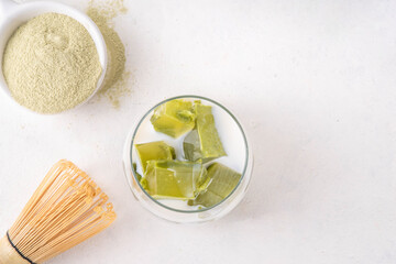 Matcha jelly latte, iced milky drink with green matcha tea jellatin cubes, trendy refreshing Iced non-caffeine healthy drink