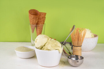 Matcha ice cream. Bowl with matcha green tea taste gellato with ice cream waffle cones. Vegan non-dairy summer dessert with matcha latte powder on top