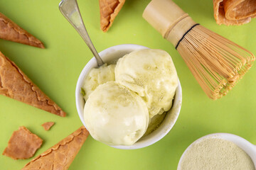 Matcha ice cream. Bowl with matcha green tea taste gellato with ice cream waffle cones. Vegan non-dairy summer dessert with matcha latte powder on top
