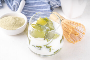 Matcha jelly latte, iced milky drink with green matcha tea jellatin cubes, trendy refreshing Iced non-caffeine healthy drink