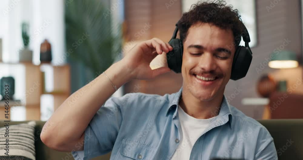 Poster headphones, dancing and man with smartphone on sofa in home for chatting, relaxing and listen to mus