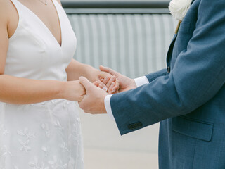 Couple holding hands during heartfelt wedding ceremony at outdoor venue in bright daylight