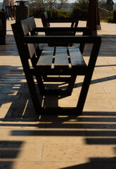 Perspective of sunlit wooden benches with linear shadows