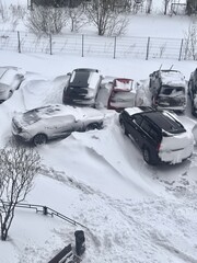 Two dozen cars trapped in snow, buried among heavy snowdrifts in a courtyard of a residential...