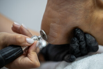 Close-up of professional pedicure using electric callus remover on heel at beauty salon